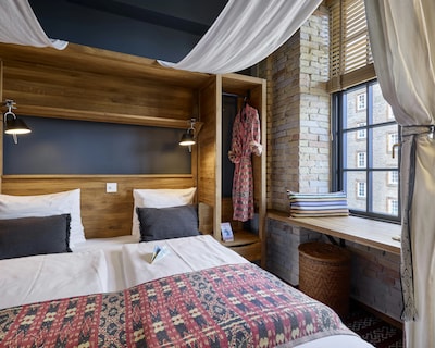 Hotelværelse med to enkeltsenge, murstensvæg og træindretning i København.