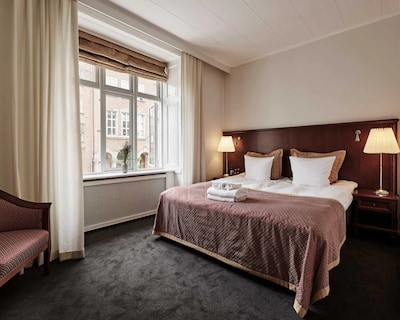 Dobbeltværelse på Hotel 66 Guldsmeden med vindue, seng og natborde.
