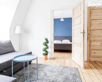 Lys lejlighed med sovesofa, soveværelse med dobbeltseng og trægulve i København.